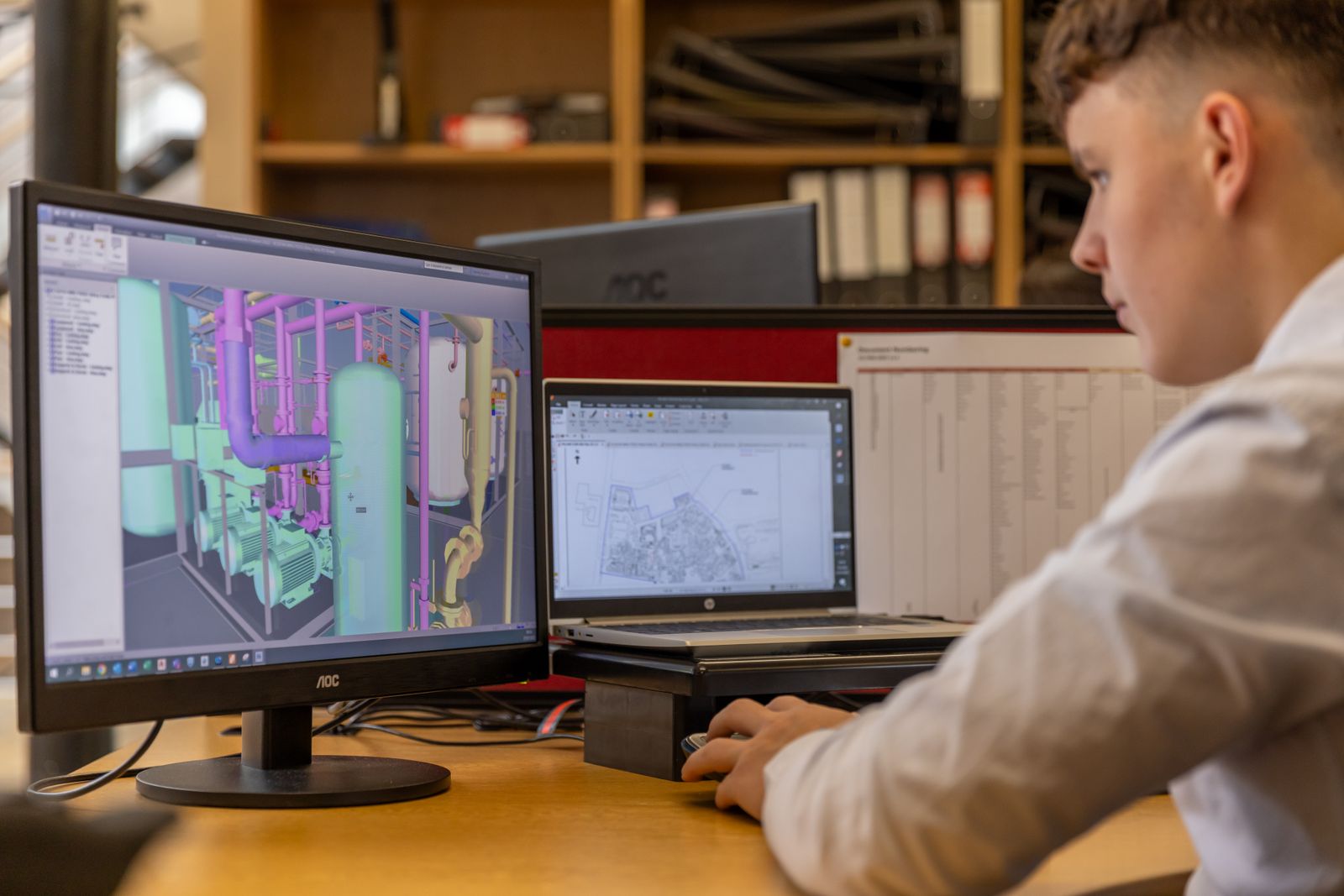 Engineer reviewing a 3D CAD model of a mechanical assembly on dual monitors